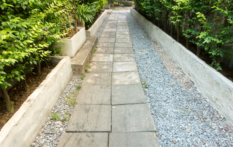 A brick walkway with gravel and trees on both sides