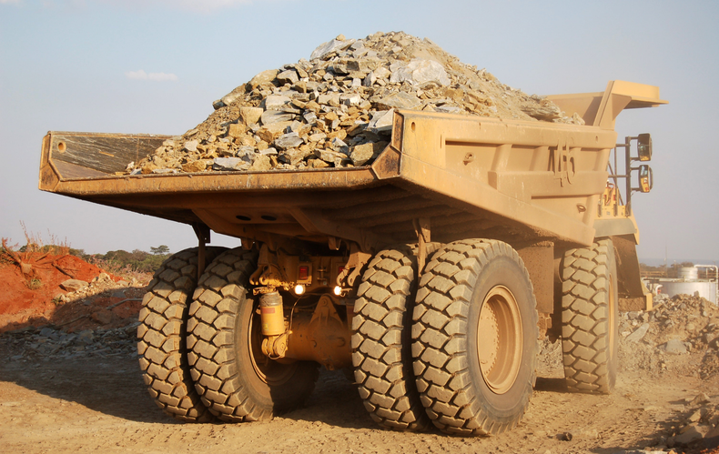 A large yellow dump truck is loaded with rocks and dirt