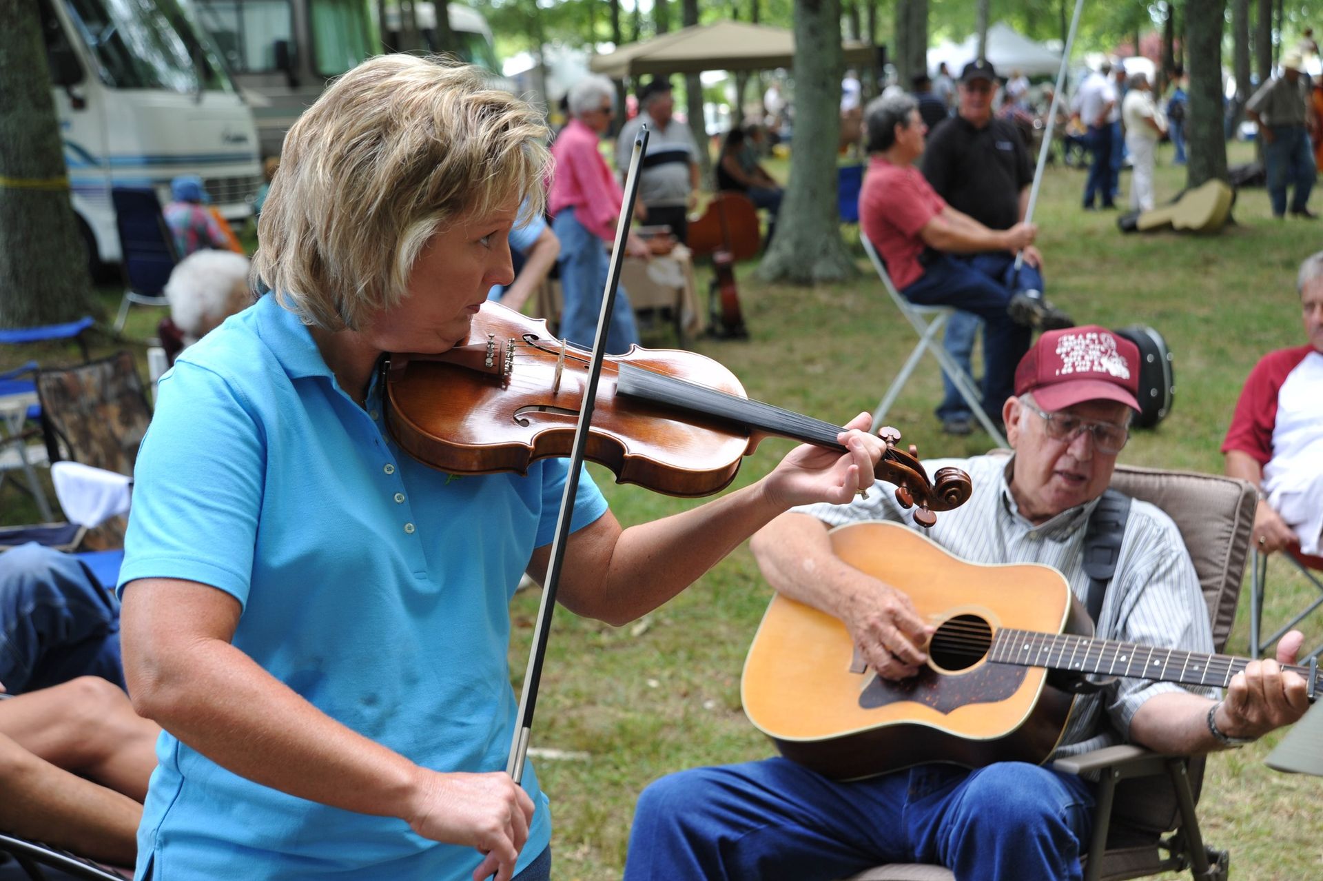 A woman is playing a violin and a man is playing a guitar