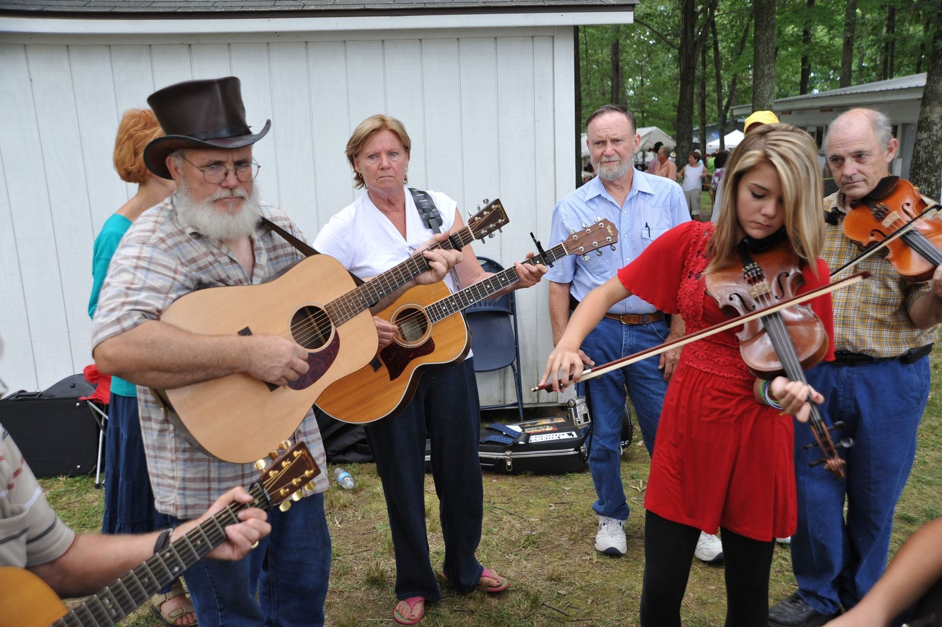 A man in a top hat is playing a guitar while a woman plays a violin