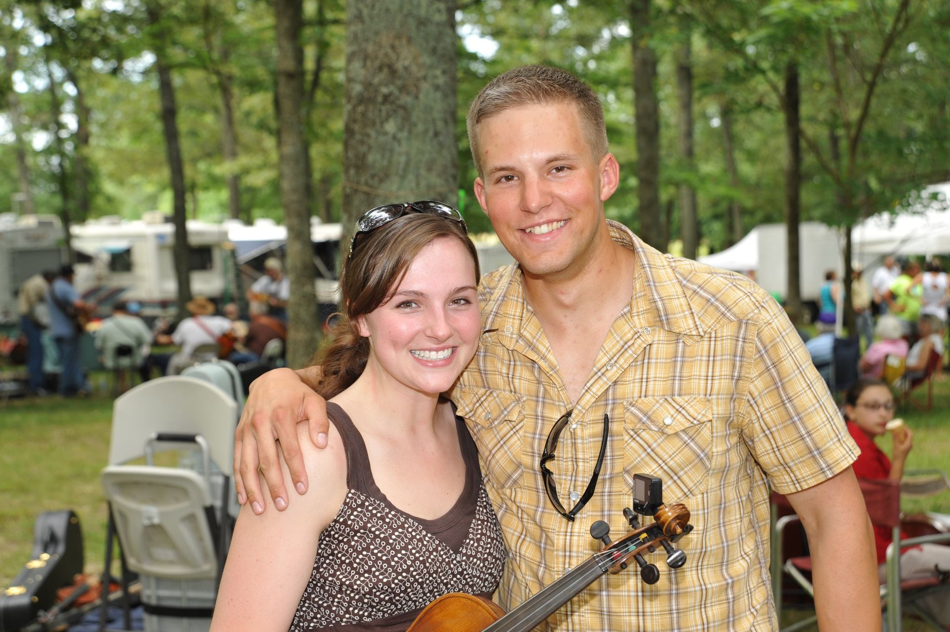 A man and a woman are posing for a picture while the woman is holding a violin.