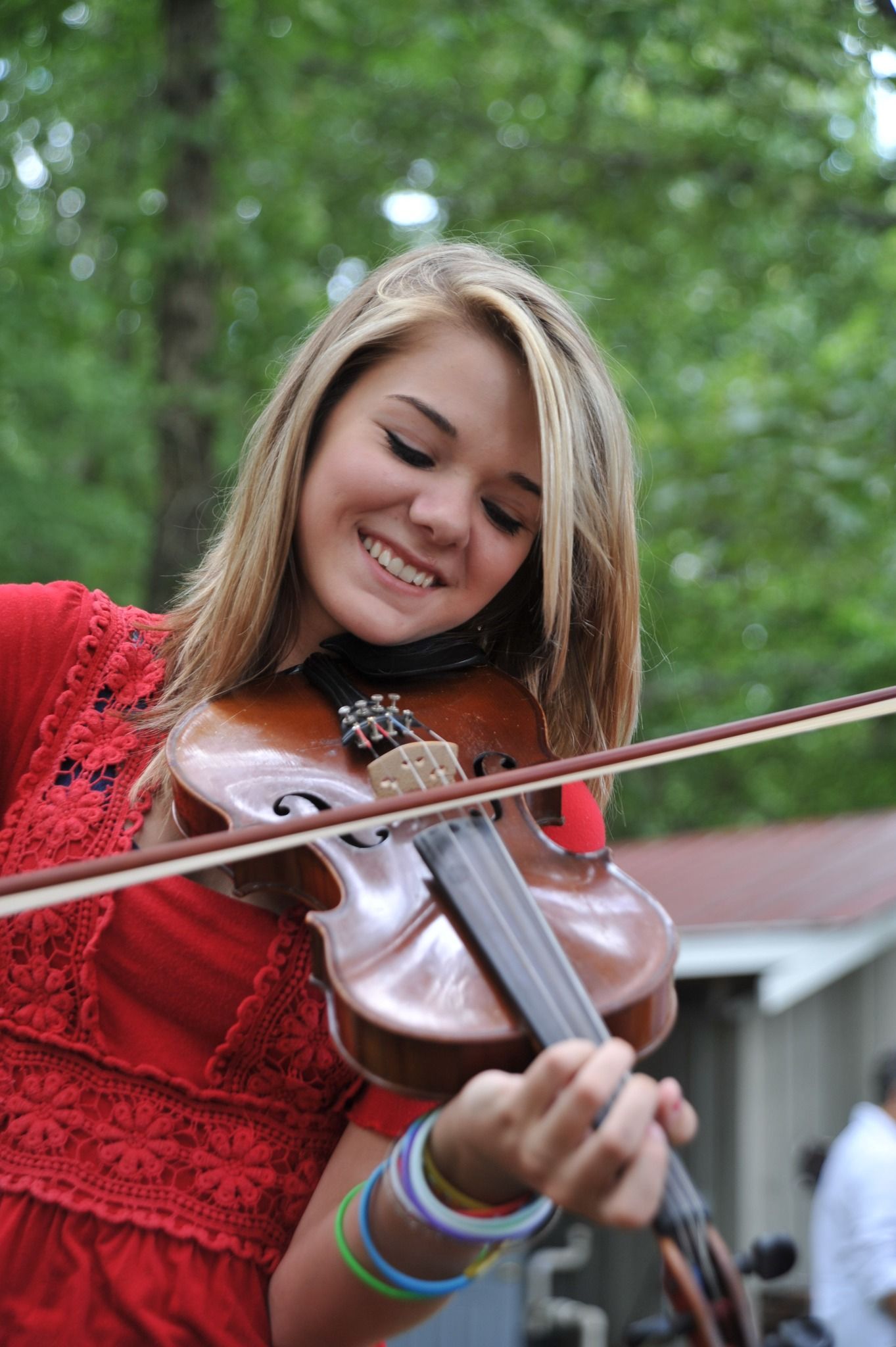 A young girl in a red dress is playing a violin