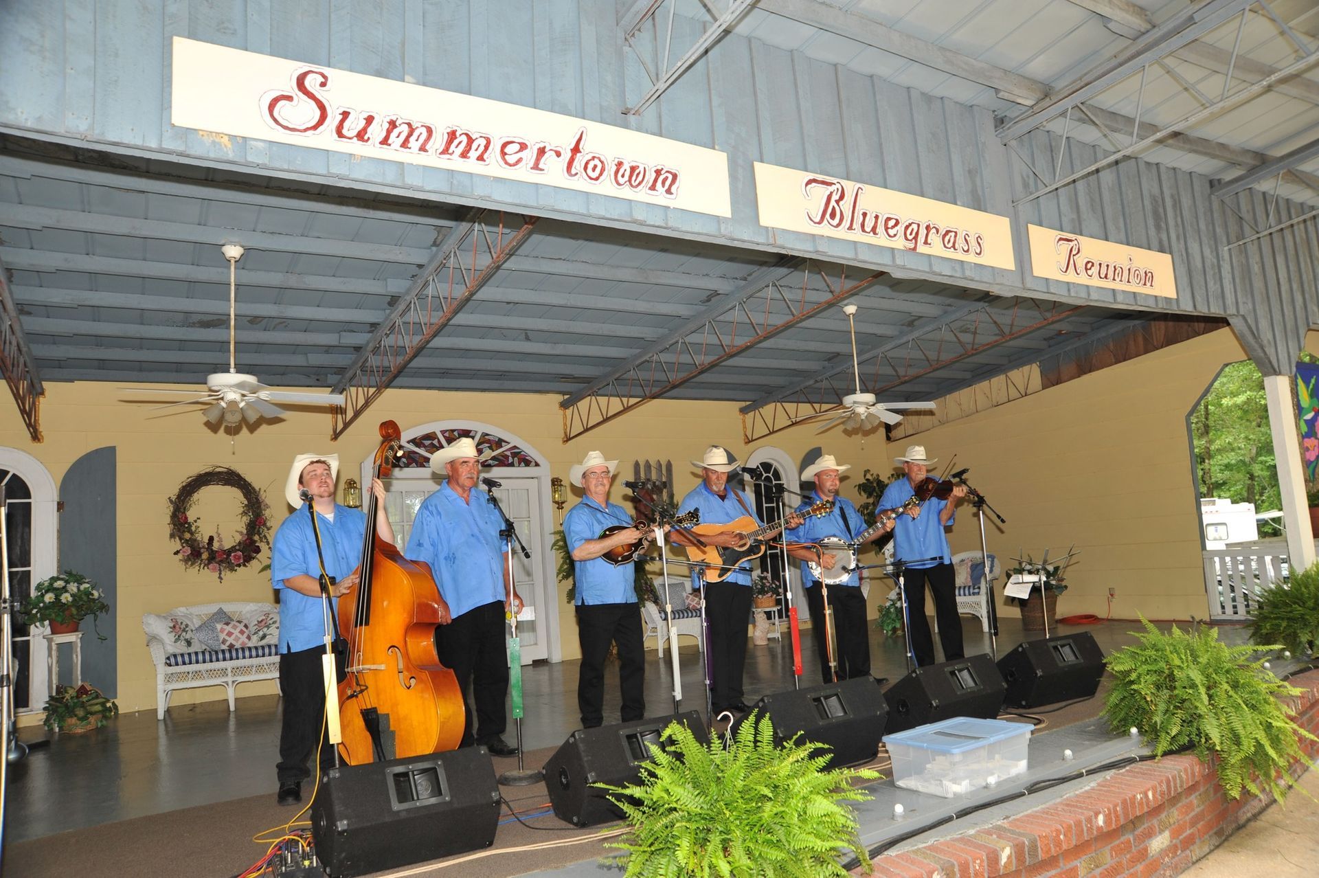 A group of men are playing instruments on a stage under a sign that says summertown.