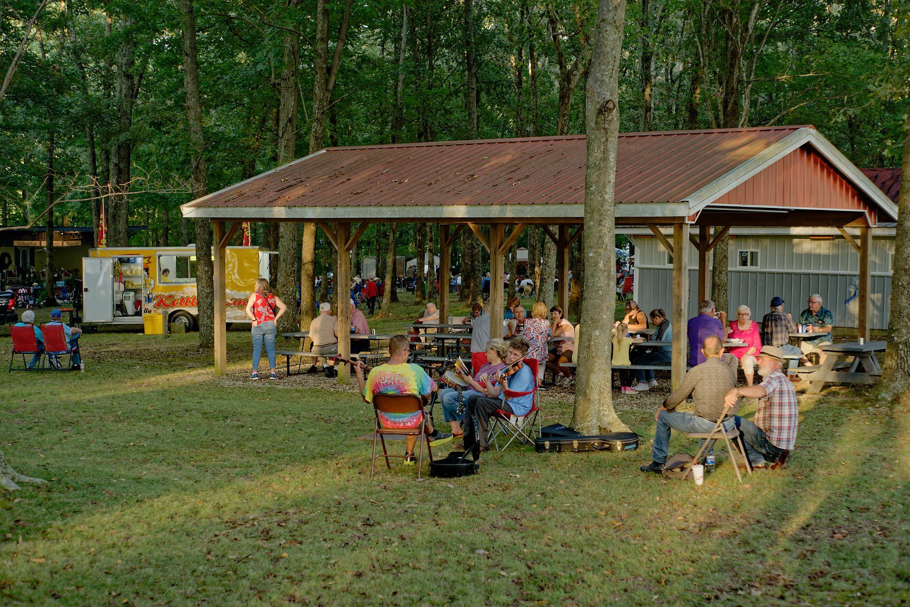 A group of people are sitting at picnic tables under a pavilion.