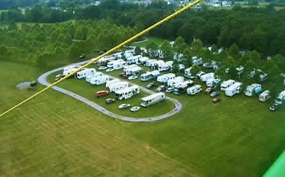An aerial view of a campground with a lot of rvs parked in the grass.