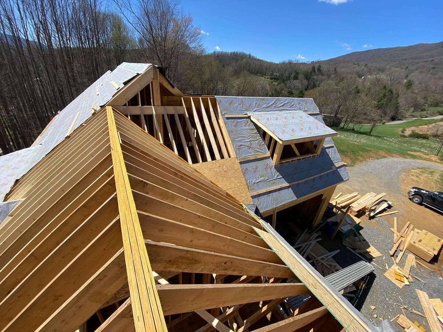 Roof framing of a house under construction with a blue sky background.