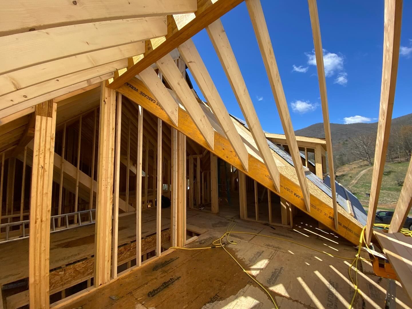 Wooden house frame under construction, clear blue sky in the background.
