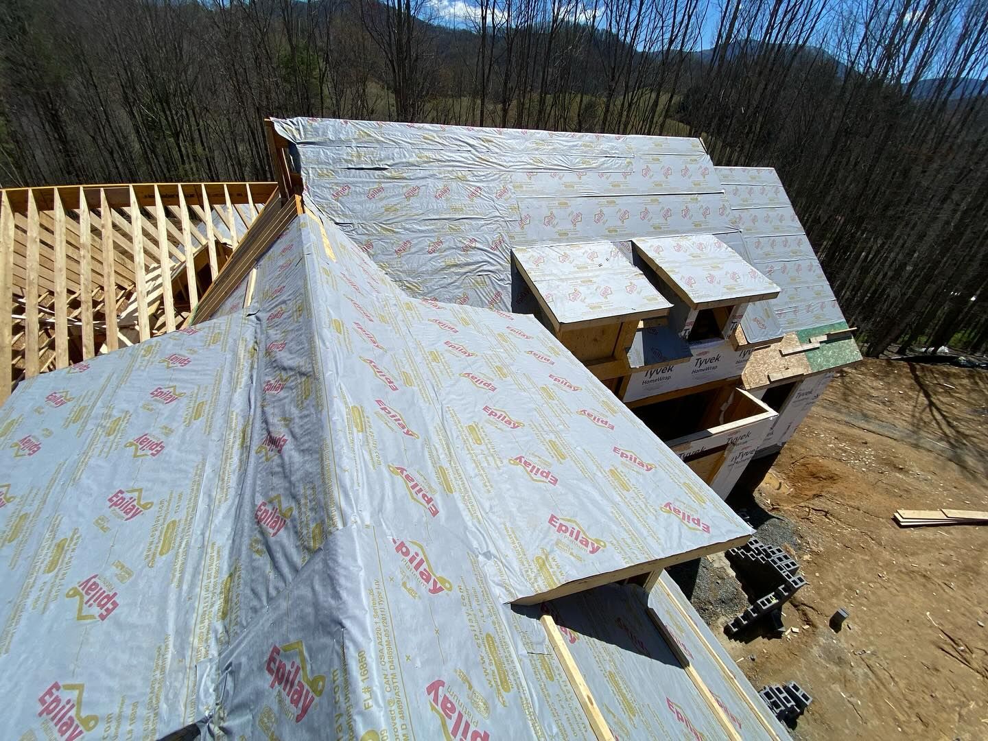 Roof construction: plywood sheathing covered in gray underlayment, wooden framing visible.