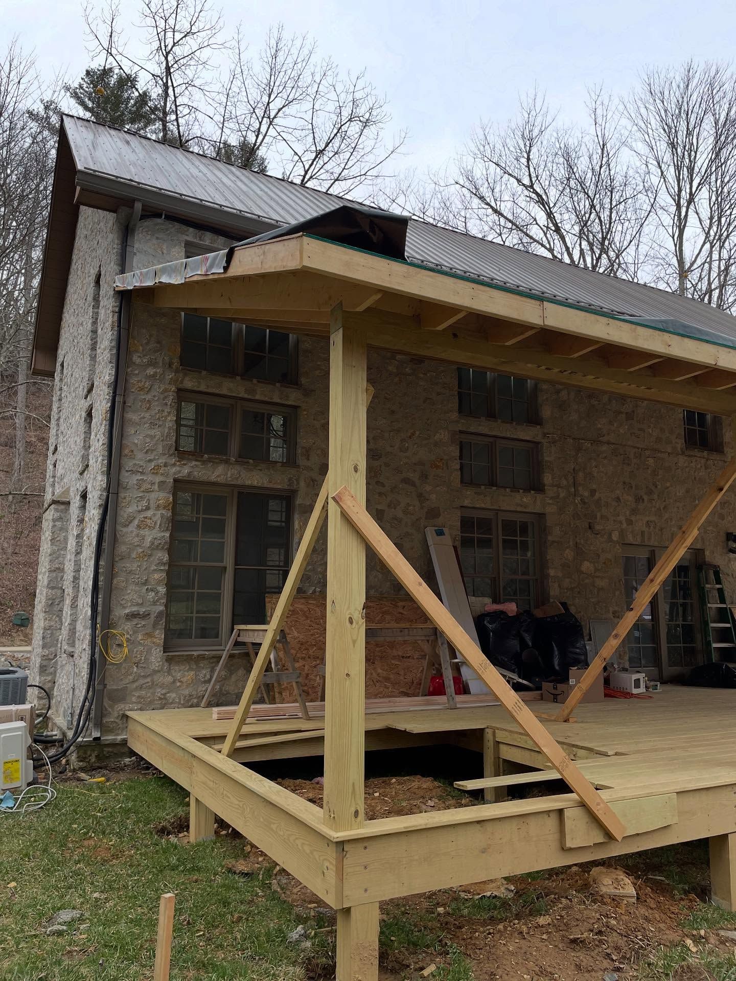 A wooden deck being built in front of an old stone building with multiple windows.