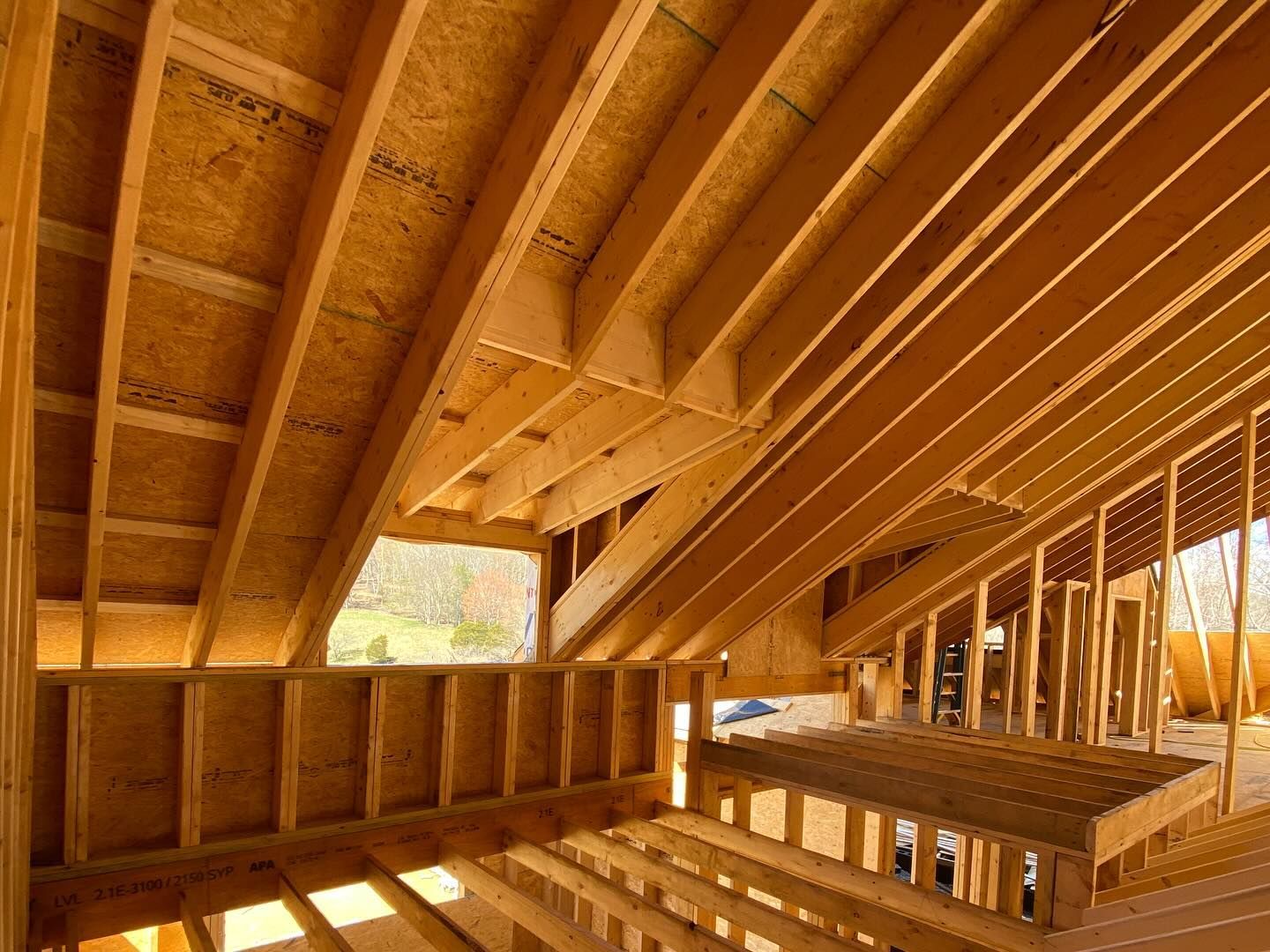 Interior framing of a building under construction, featuring wooden beams and rafters.