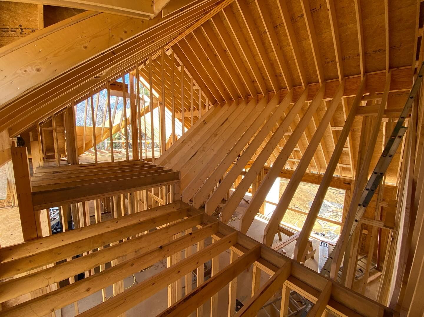Wooden framework of a building's interior under construction, showing rafters, beams, and an open loft area.