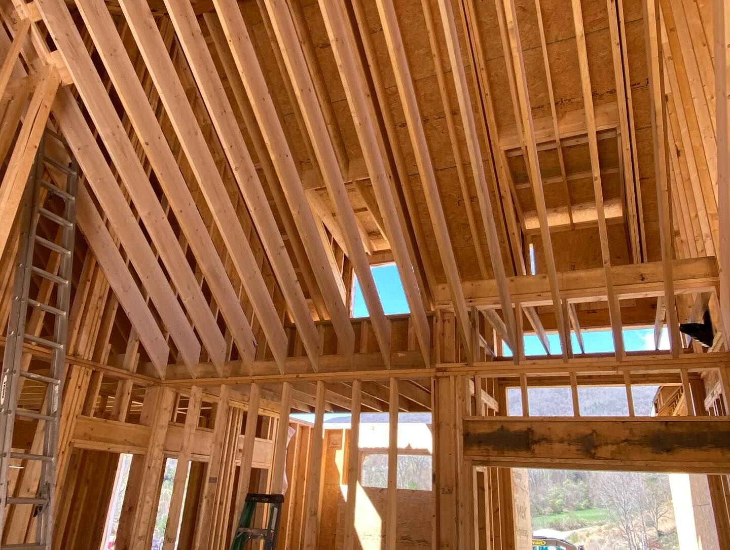 Interior view of a building under construction, showing wooden framing for walls and ceiling, sunlight visible.