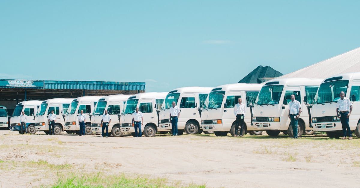 A row of white buses parked next to each other in a parking lot.  | Lux AutoHause