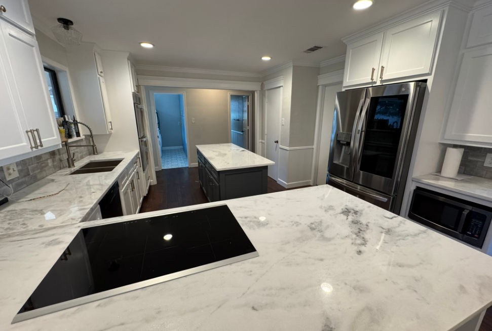 Modern kitchen with white cabinets, marble countertops, stainless steel appliances, and two islands.