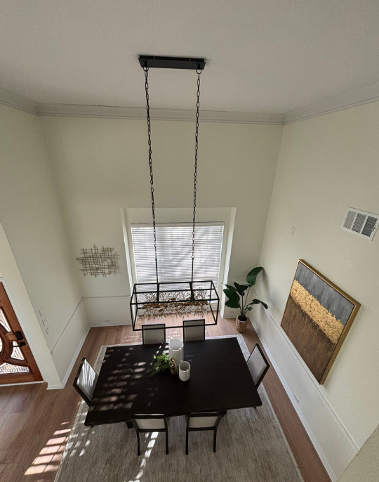 Dining room with a dark square table, chairs, and a long pendant light fixture.