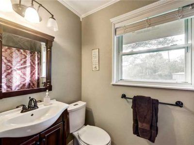 Bathroom with a vanity, toilet, and window; brown and white color scheme.