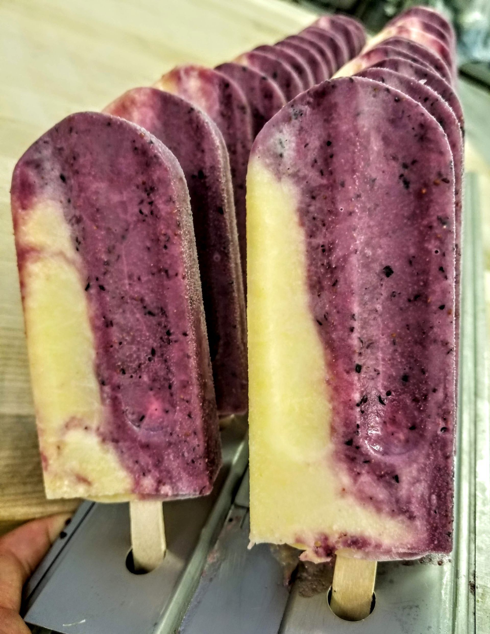 A row of blue popsicles are sitting on a table.