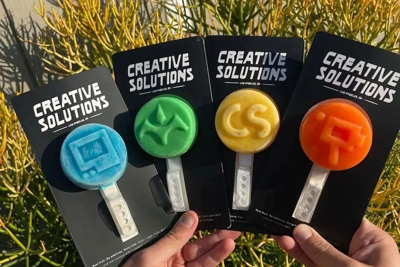 A person is holding four different colored creative solutions pops