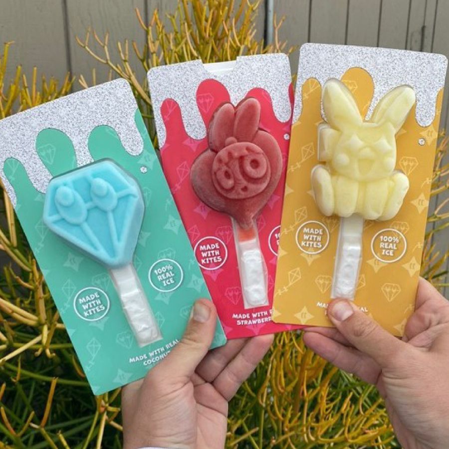 A person is holding three different shaped lollipops in their hands.