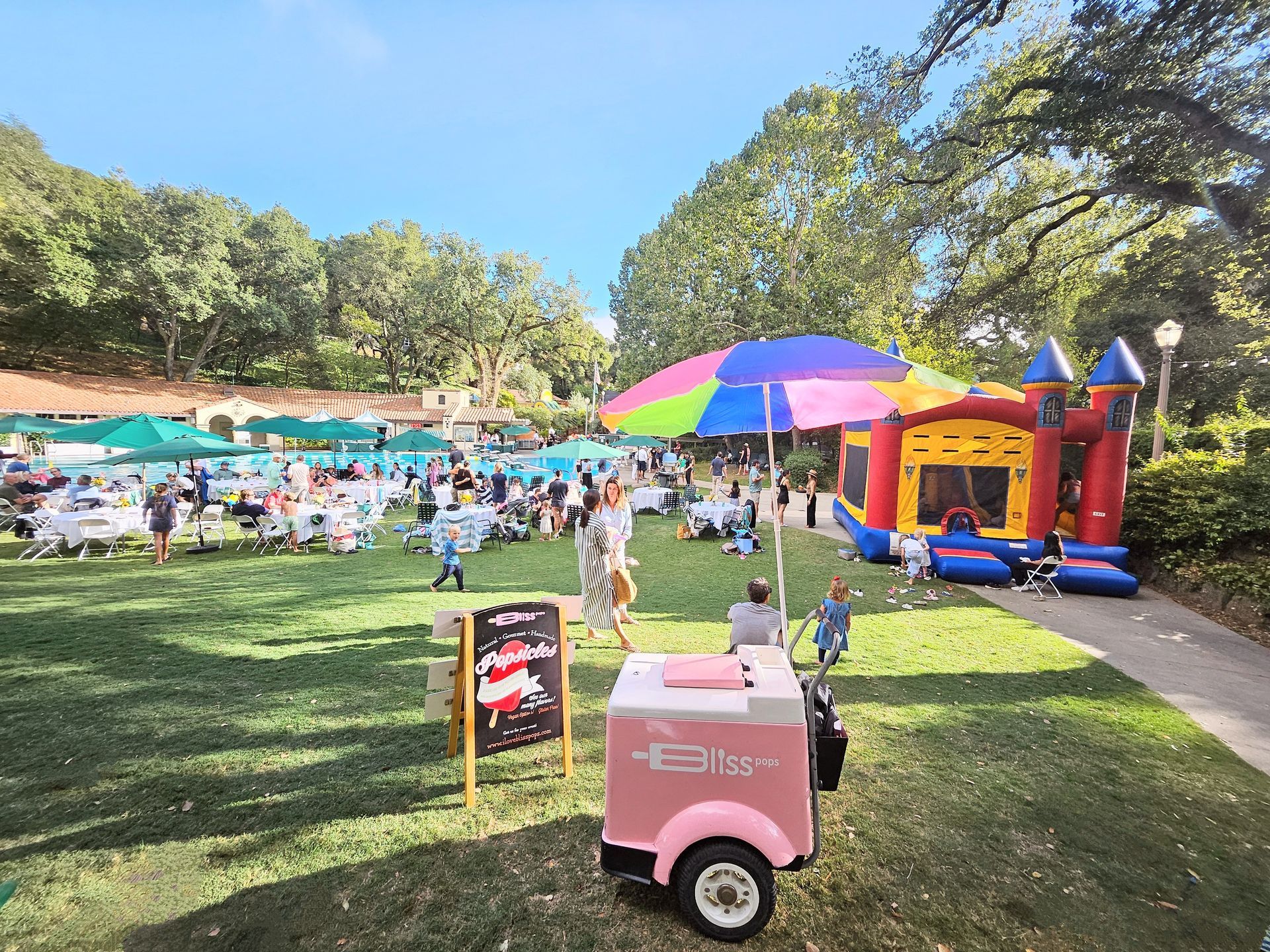 An ice cream cart is parked in the grass next to a sign.