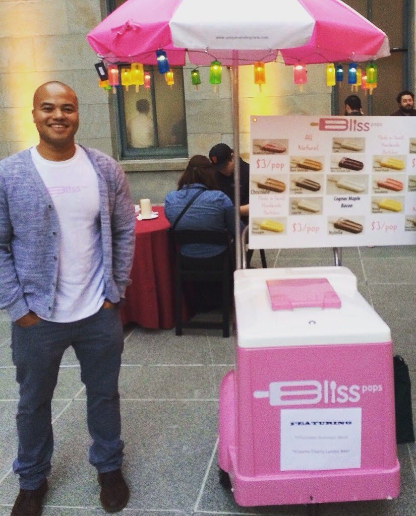 A man standing next to a pink bliss cart