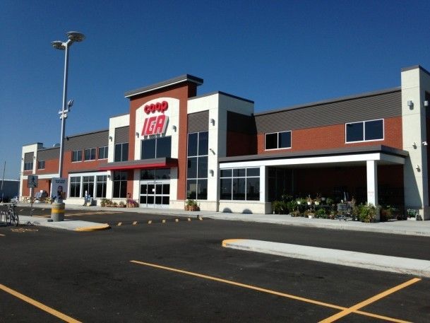 Extérieur d'une épicerie, IGA, avec une façade en brique, des fenêtres et un ciel bleu.