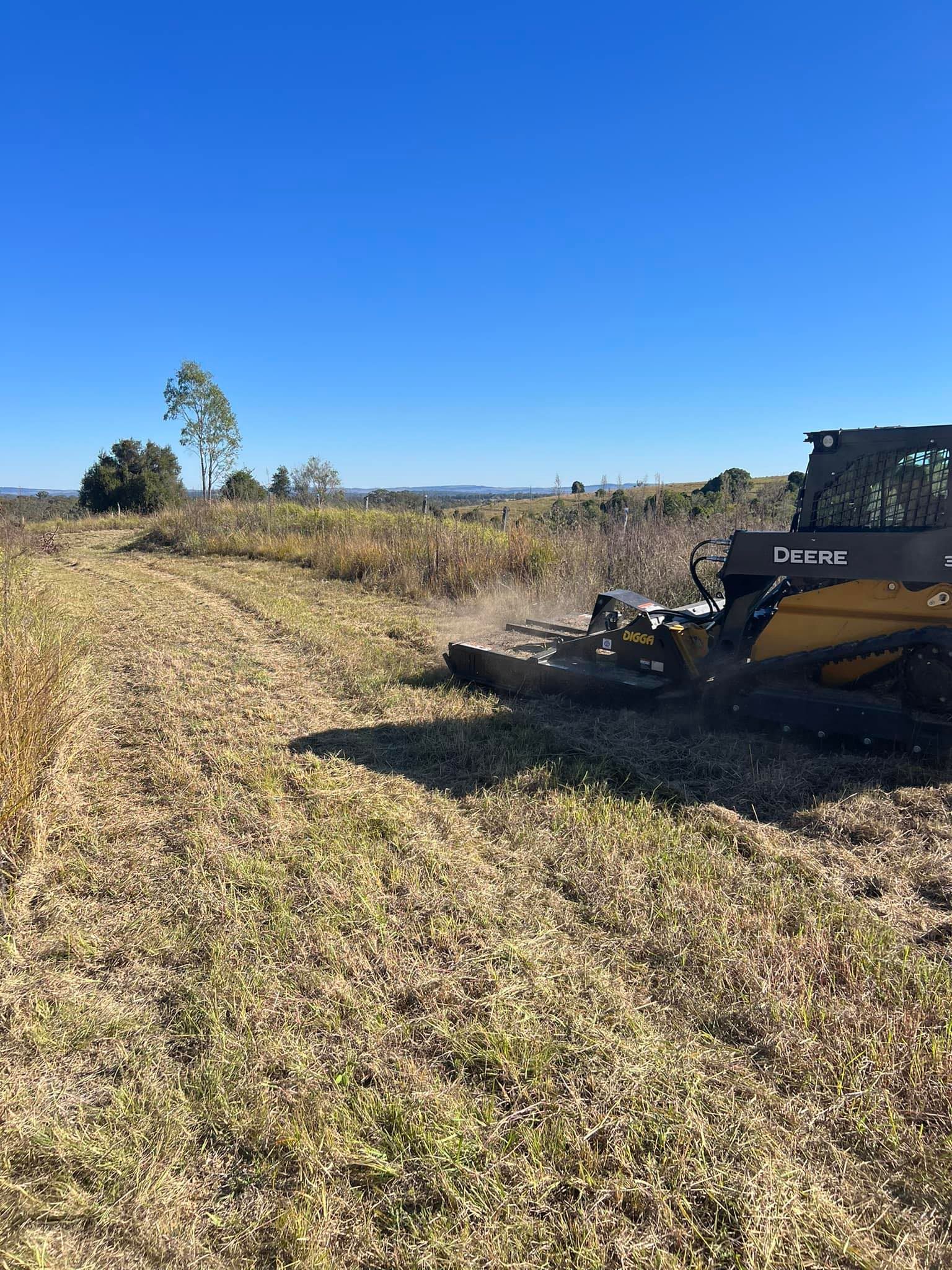 A John Deere Skid Steer With a Mower Attachment Cutting Tall Grass in a Field — Dudgeon’s Earthworks in Murgon, QLD