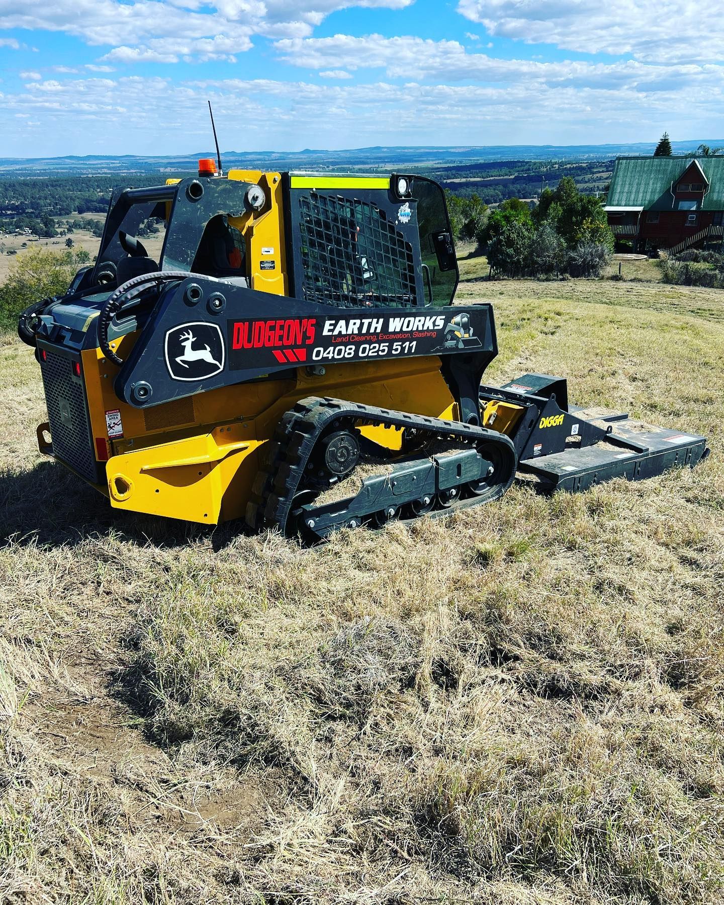 Yellow John Deere Skid Steer With Mower Attachment on a Grassy Hill With a View — Dudgeon’s Earthworks in Murgon, QLD