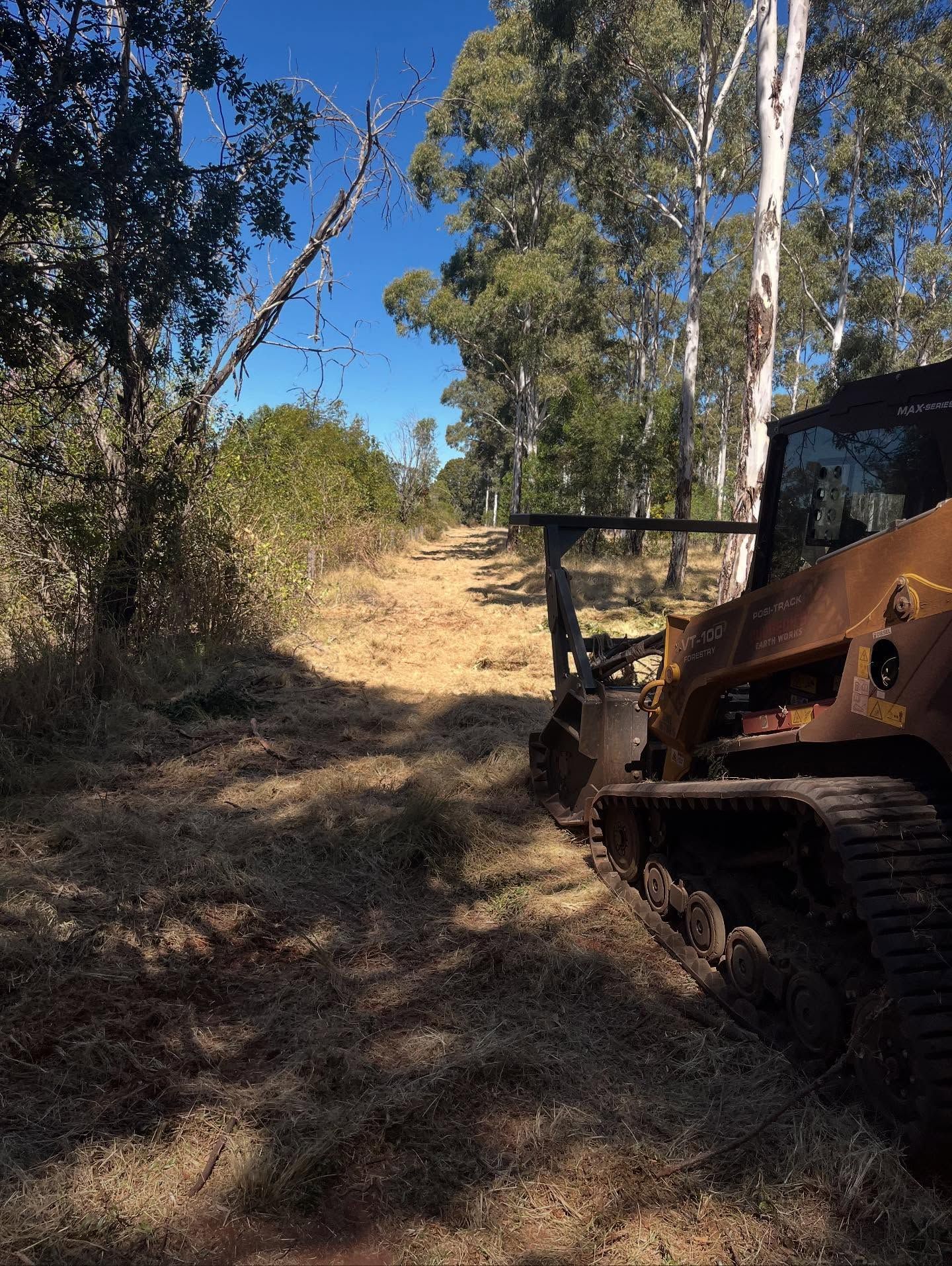 A Bulldozer Clearing a Dirt Path Through Dry Grass and Trees Under a Blue Sky — Dudgeon’s Earthworks in Murgon, QLD