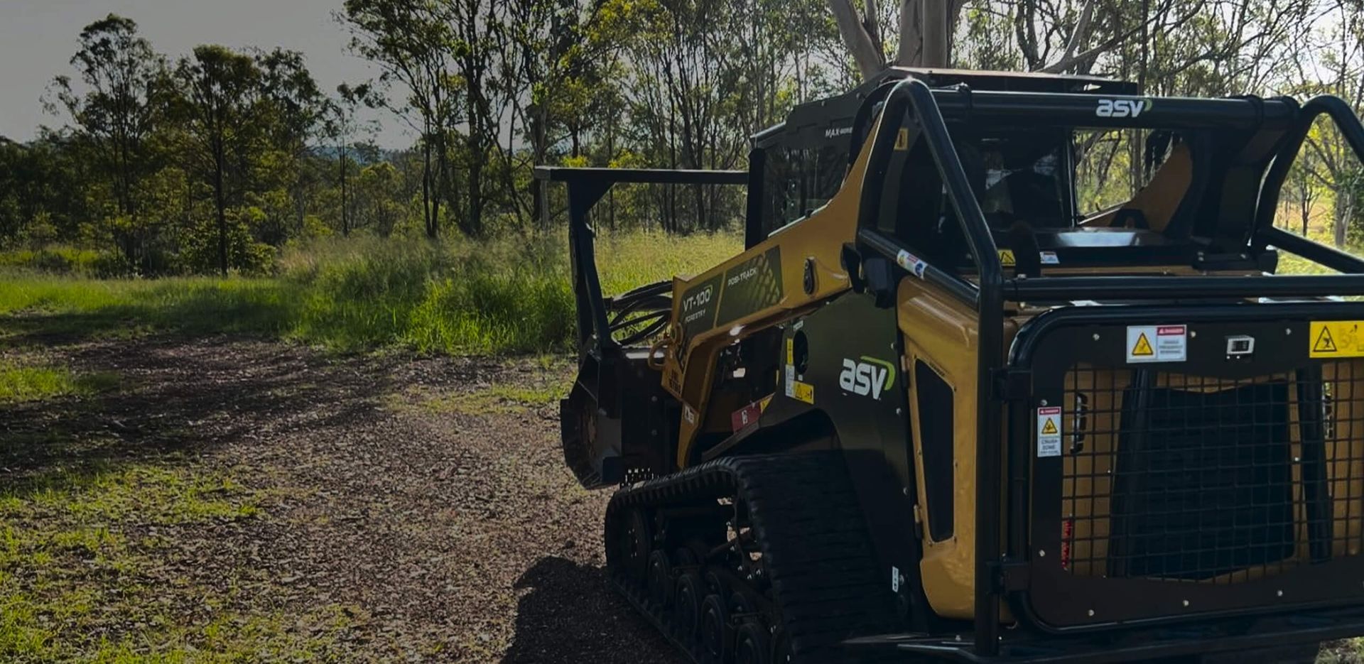 Yellow and Black Track Loader on a Dirt Path in a Grassy, Wooded Area — Dudgeon’s Earthworks in Murgon, QLD