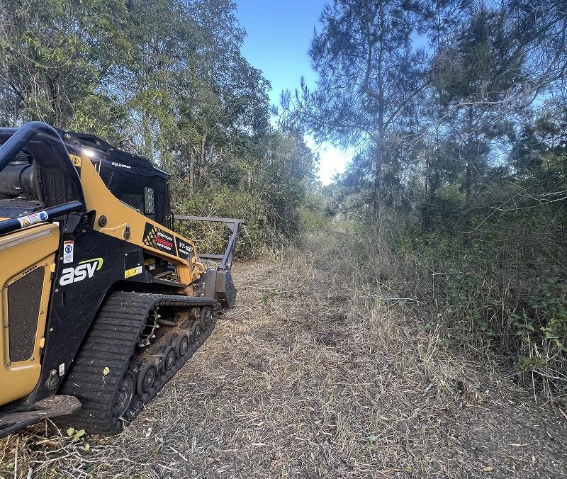 A Small Yellow Track Machine Clearing a Brush-filled Path in a Wooded Area — Dudgeon’s Earthworks in Murgon, QLD