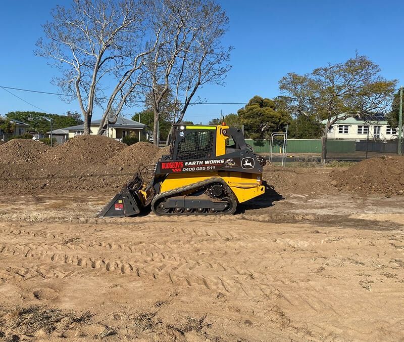 Yellow Skid Steer Tractor on a Dirt Surface, Next to a Pile of Dirt — Dudgeon’s Earthworks in Murgon, QLD