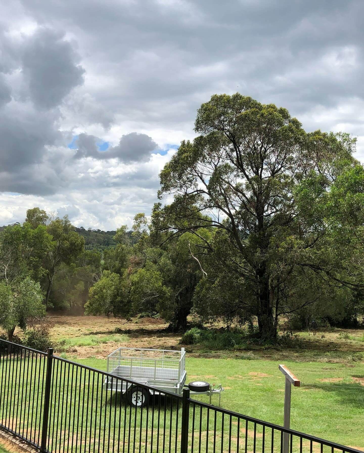 Grassy Yard With Trees, Cloudy Sky, and a Trailer Behind a Black Fence — Dudgeon’s Earthworks in Murgon, QLD