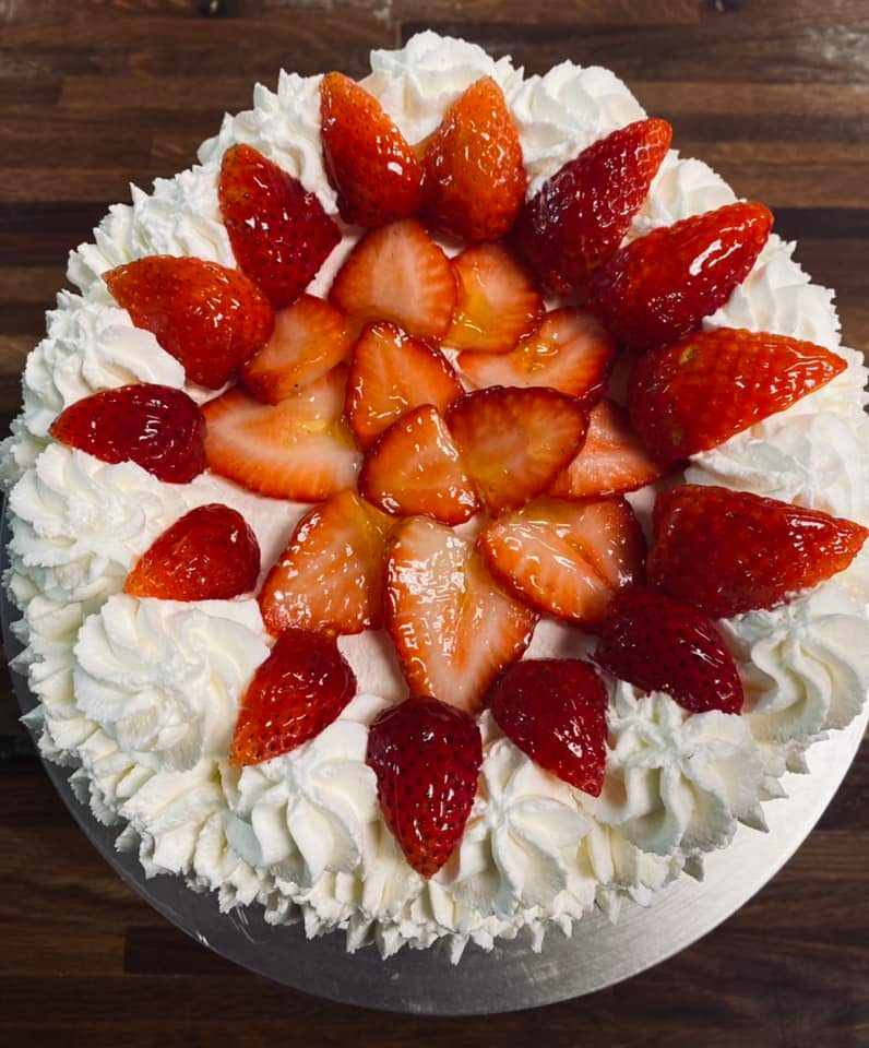 Cake with white frosting and fresh strawberry slices on top.