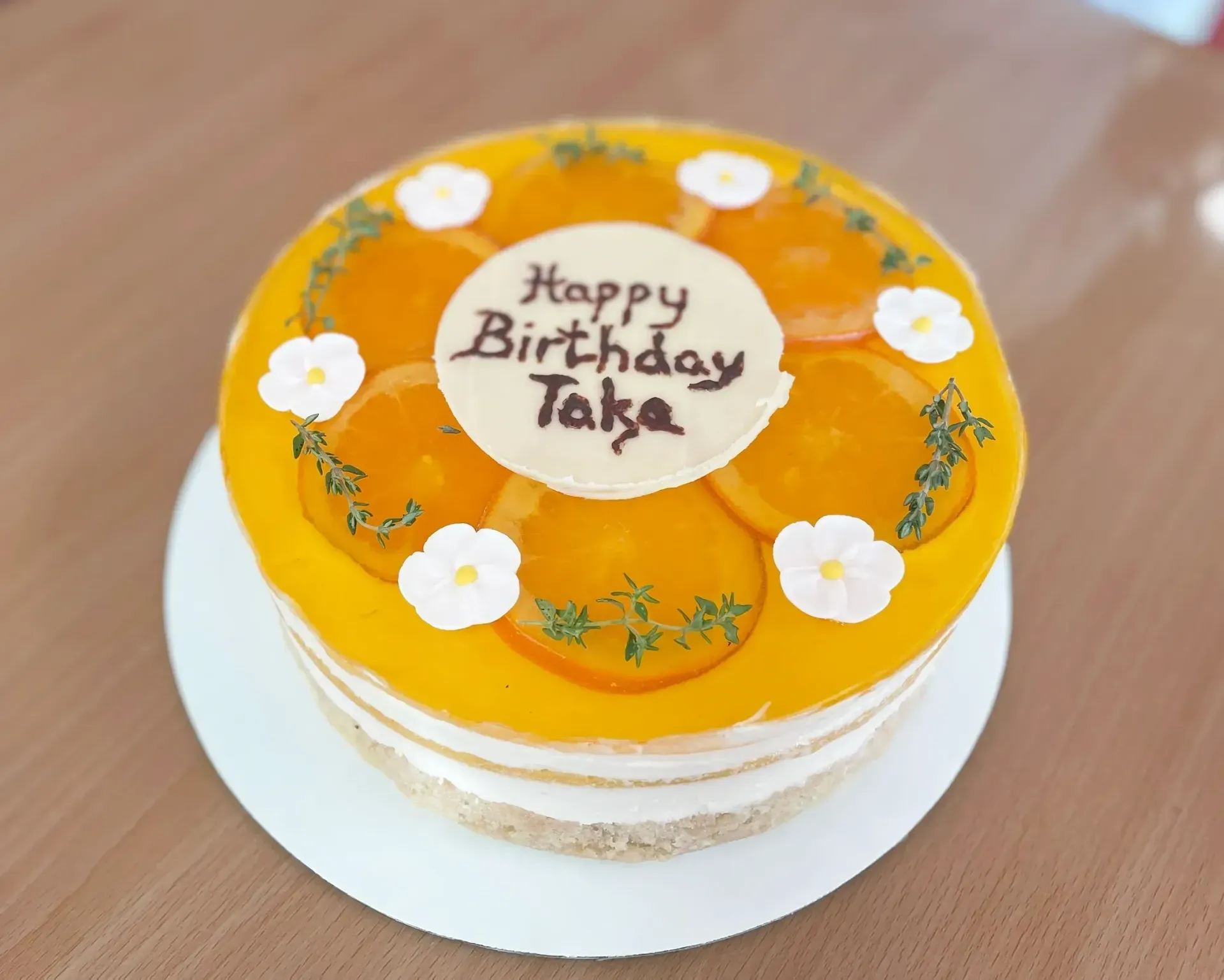 Birthday cake with orange glaze, peach slices, floral accents, and 