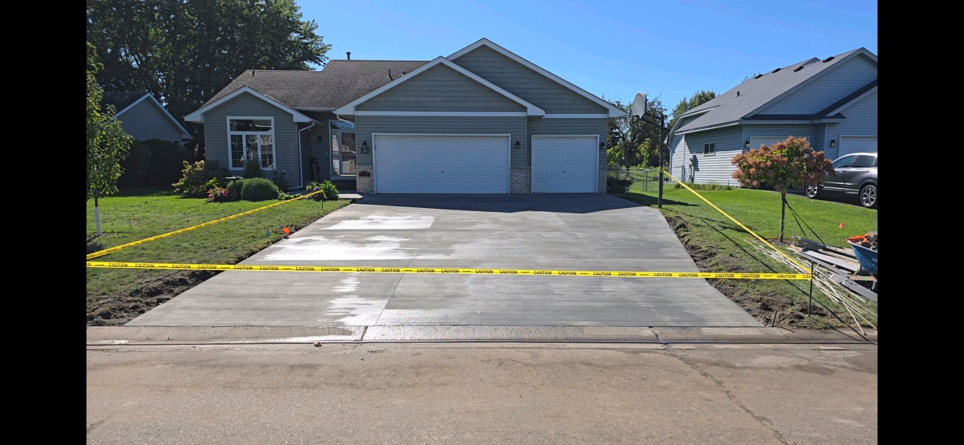 A house with a driveway blocked by yellow caution tape on a sunny day.