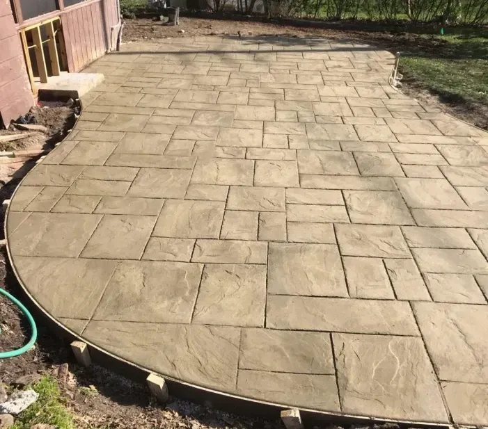 Stamped concrete patio, tan color, irregular rectangular pattern, curved edge, next to building.