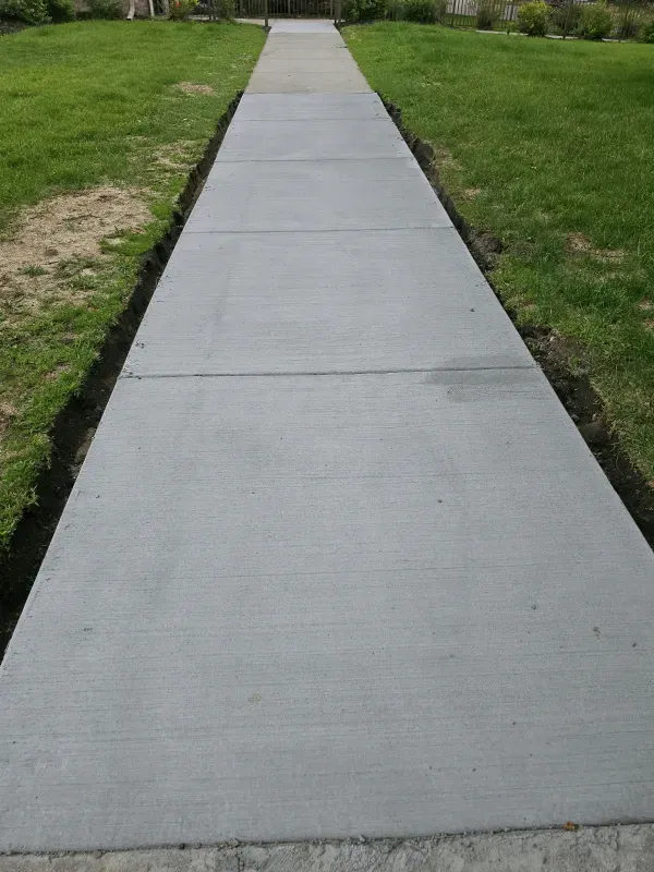 Concrete sidewalk extending through green grass.