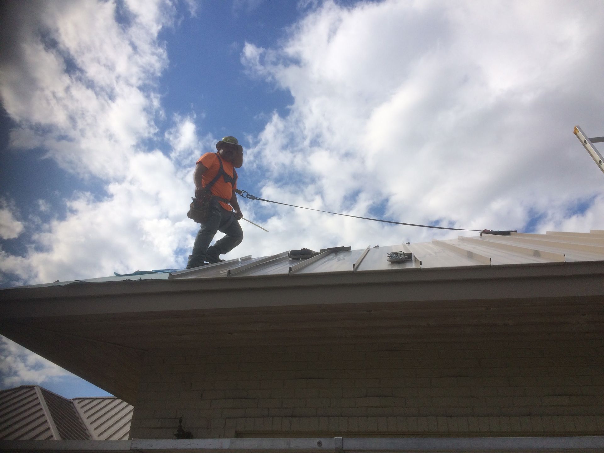 A man is standing on top of a roof holding a rope.