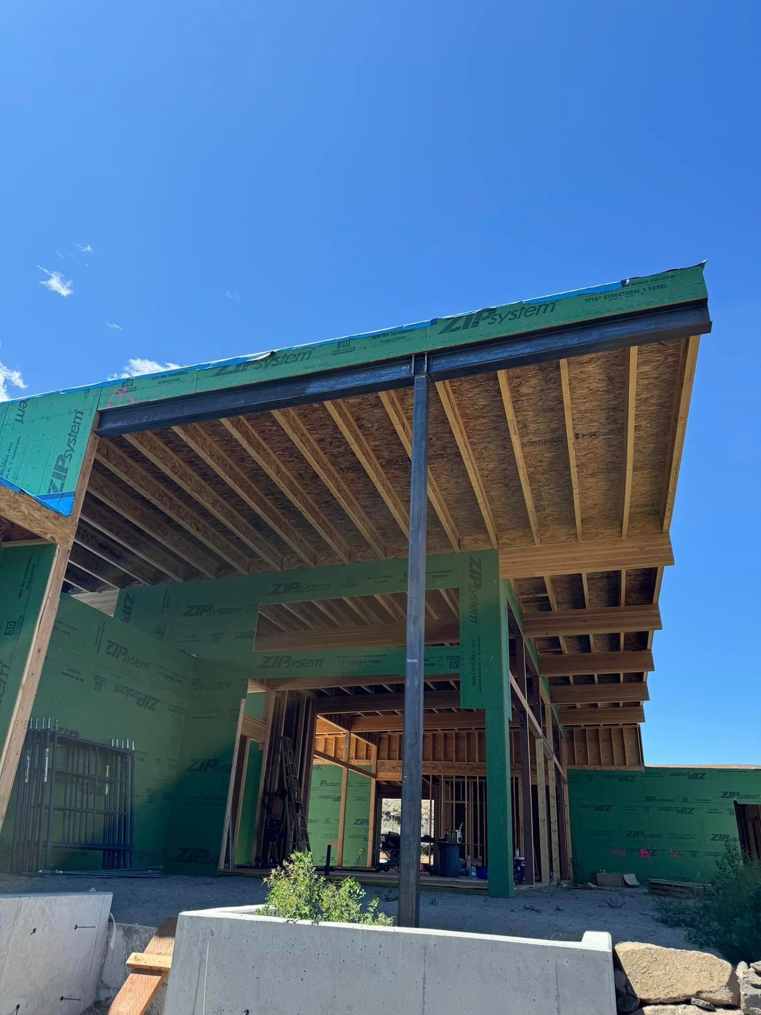A house is being built with a green roof and a blue sky in the background.