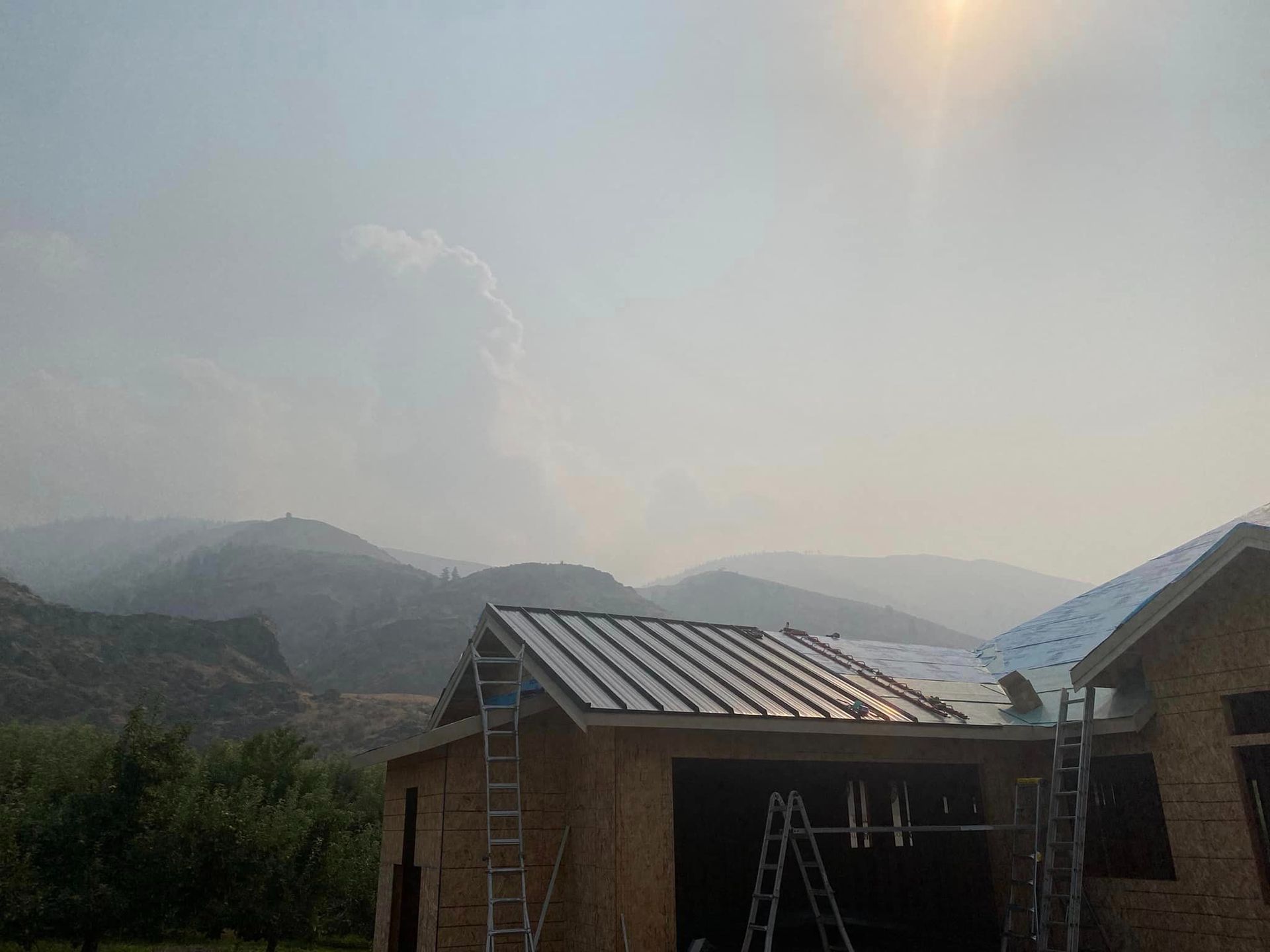 A house with a metal roof is being built in the mountains.
