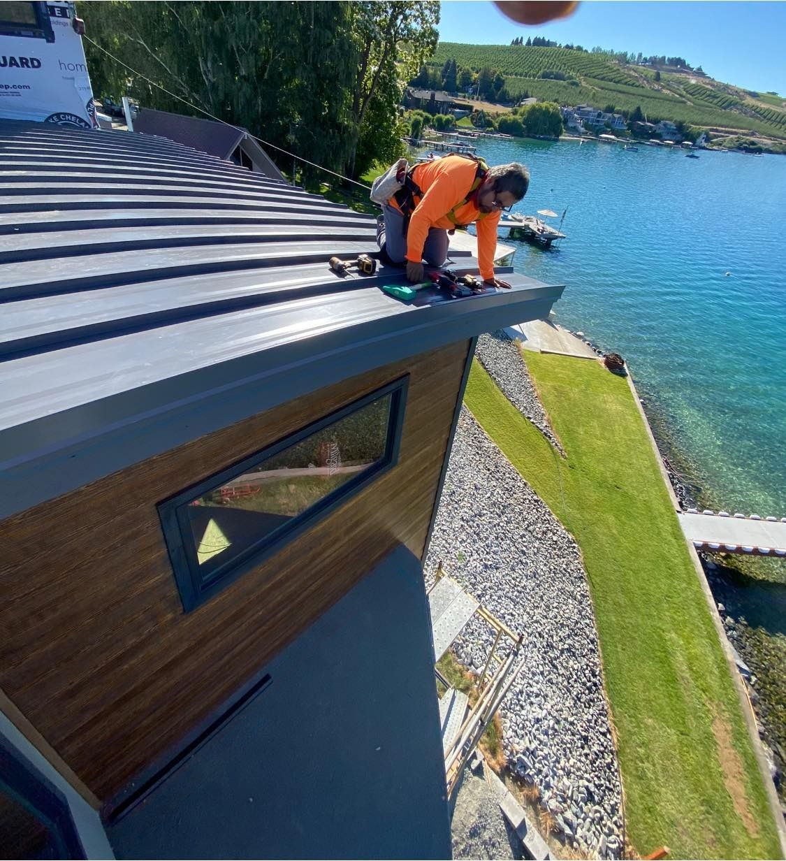 A man is working on the roof of a house near the water