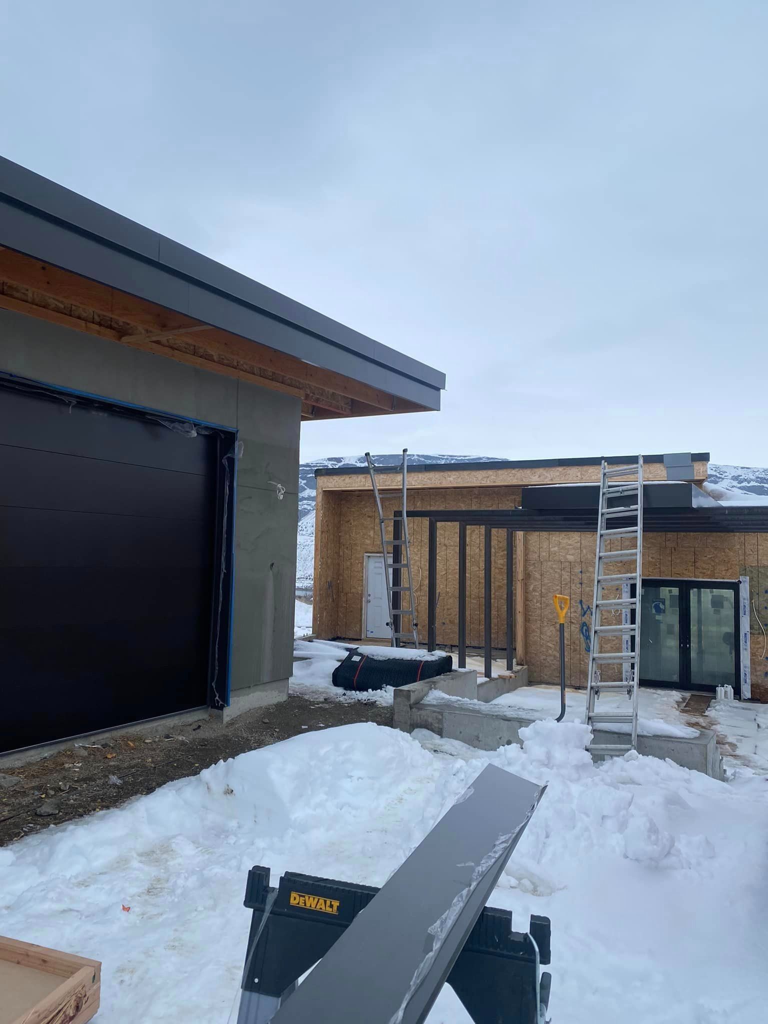 A house is being built in the snow with a ladder in front of it.
