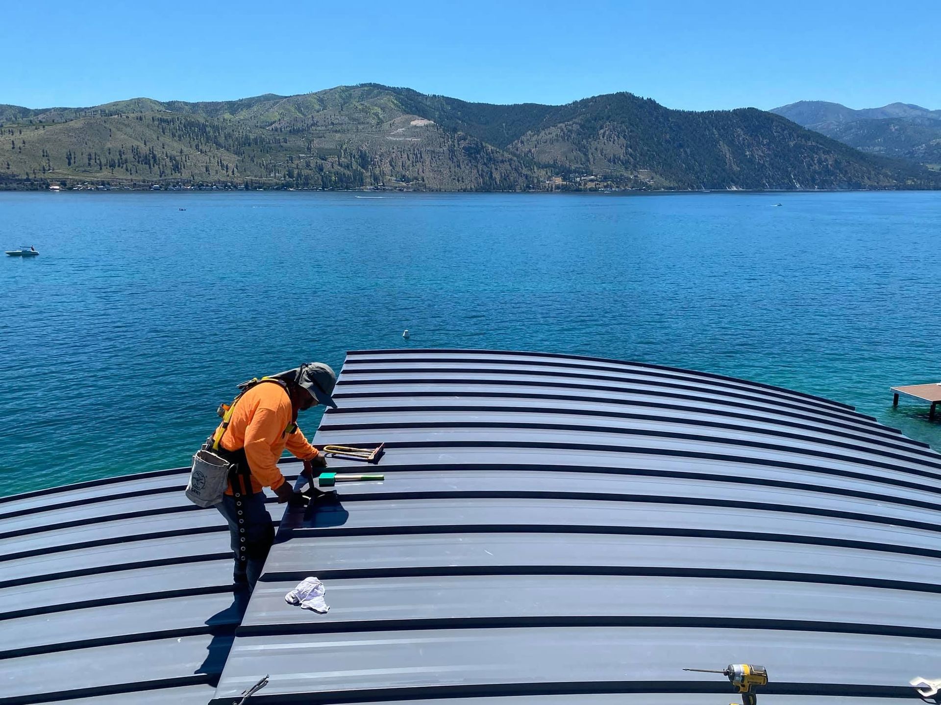 A man is working on a roof overlooking a lake.