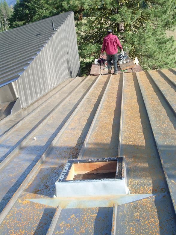 A man is standing on top of a metal roof.