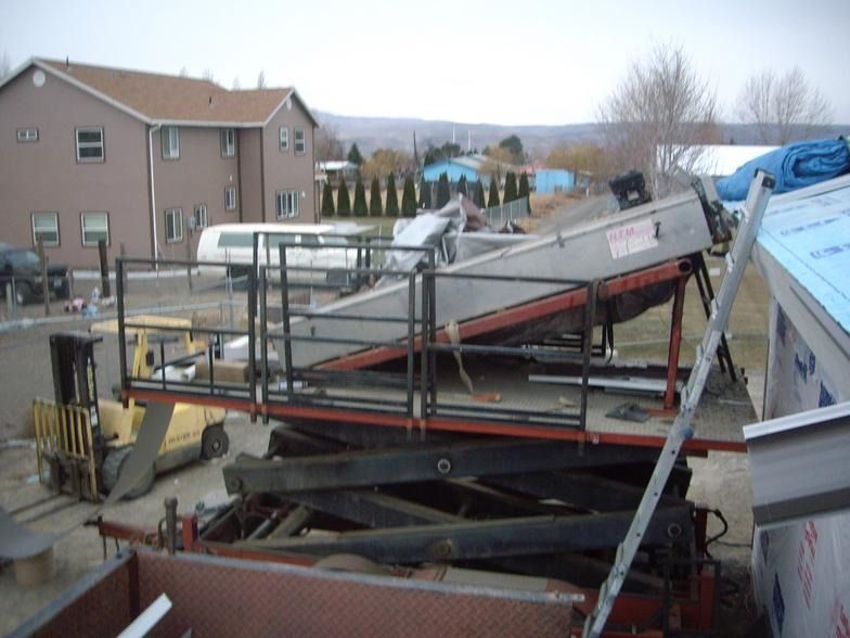 A forklift is parked in front of a building with a blue tarp on the roof