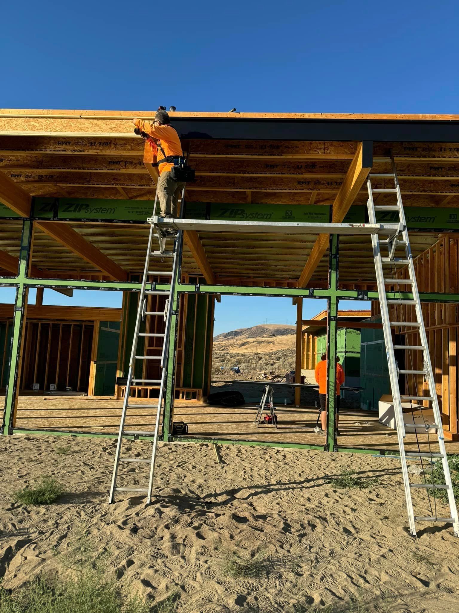 A man is standing on a ladder working on the roof of a building.