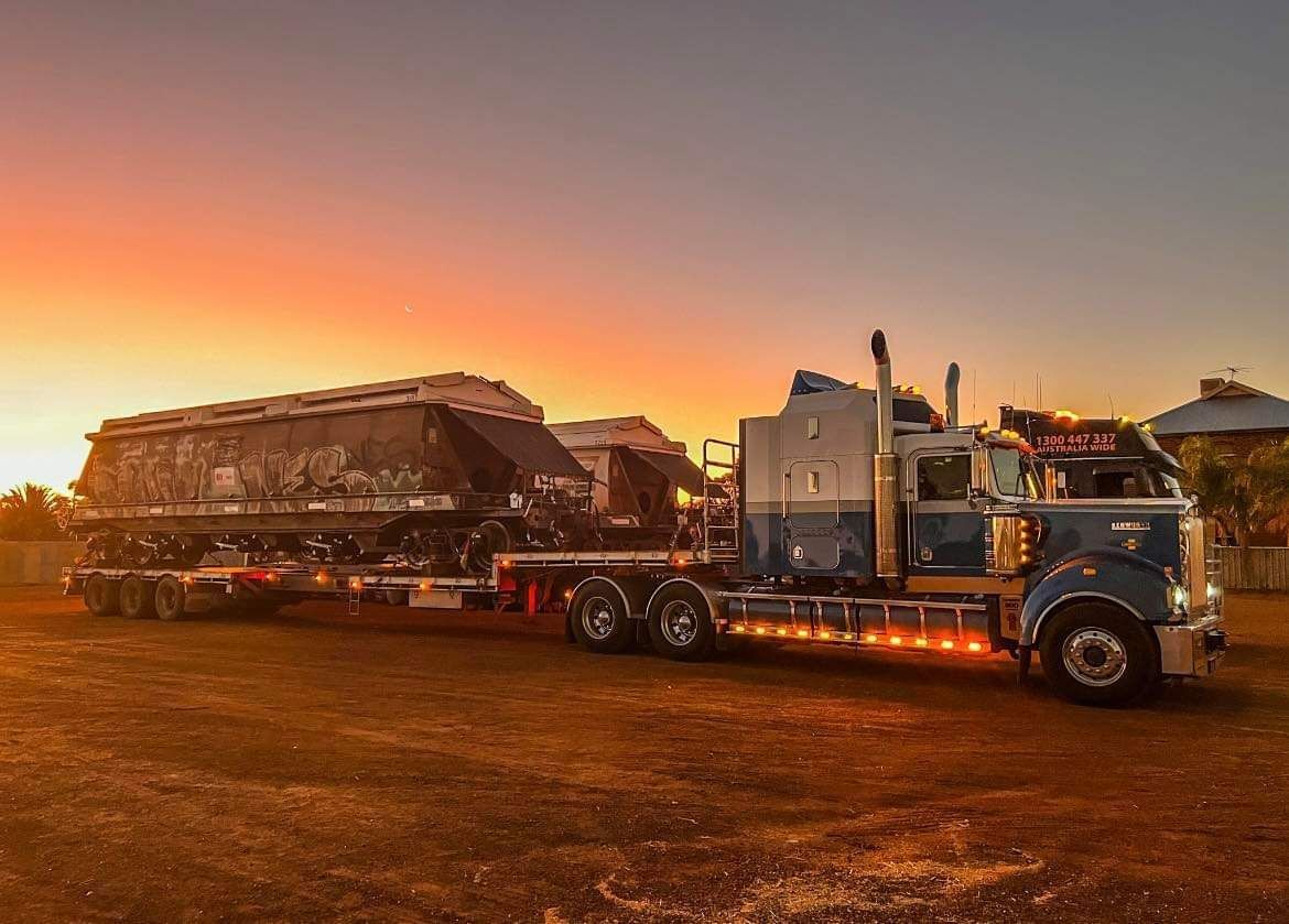 Blue semi-truck with a trailer, parked on dirt at sunset — ECC Heavy Haulage in Ormeau, QLD