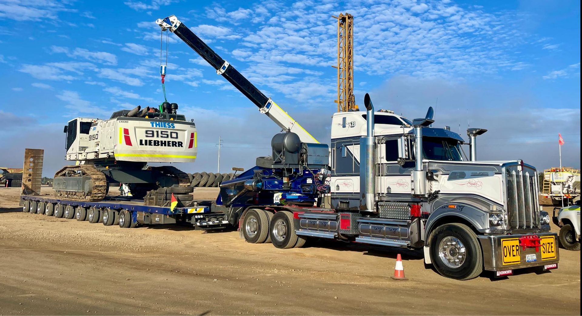 Heavy machinery being transported on a flatbed truck with a crane — ECC Heavy Haulage in Ormeau, QLD