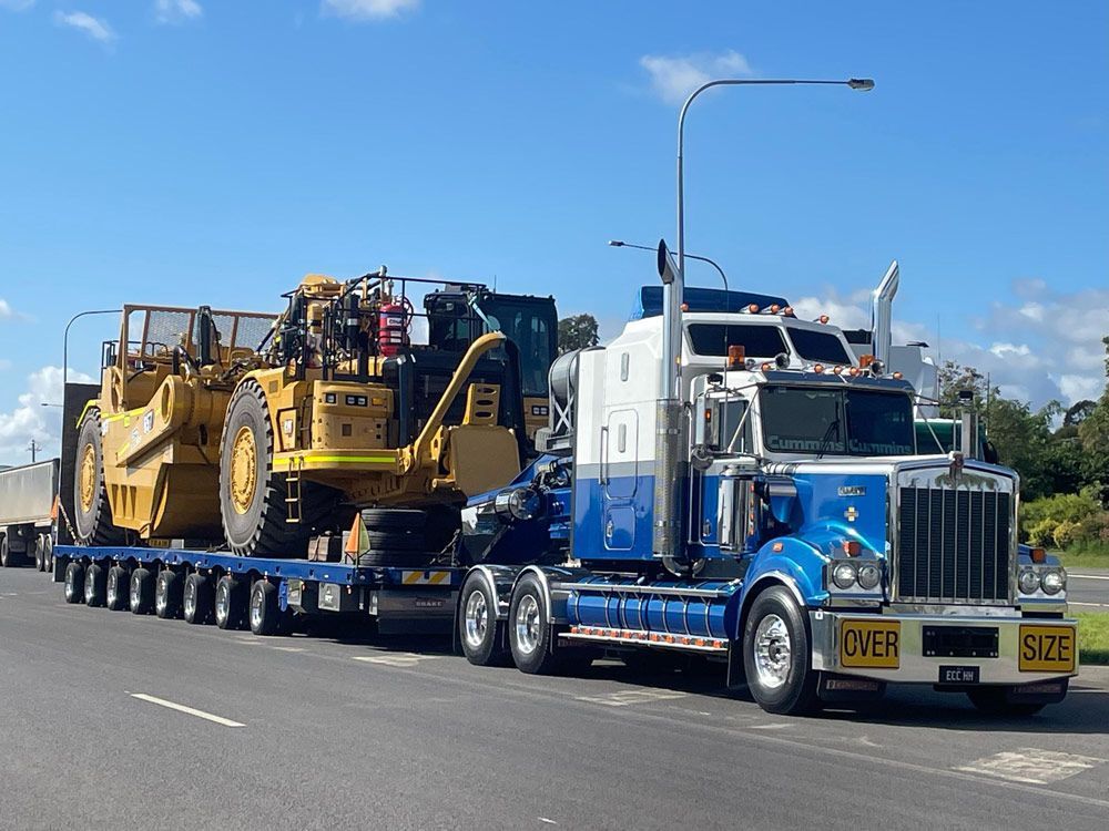 A Large Semi-truck Transports Yellow Construction Equipment — ECC Heavy Haulage in Gold Coast, QLD